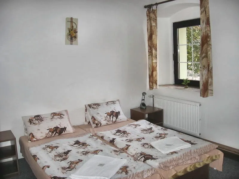 Pokoj s manželskou postelí, povlečením s koňmi a oknem do zeleně